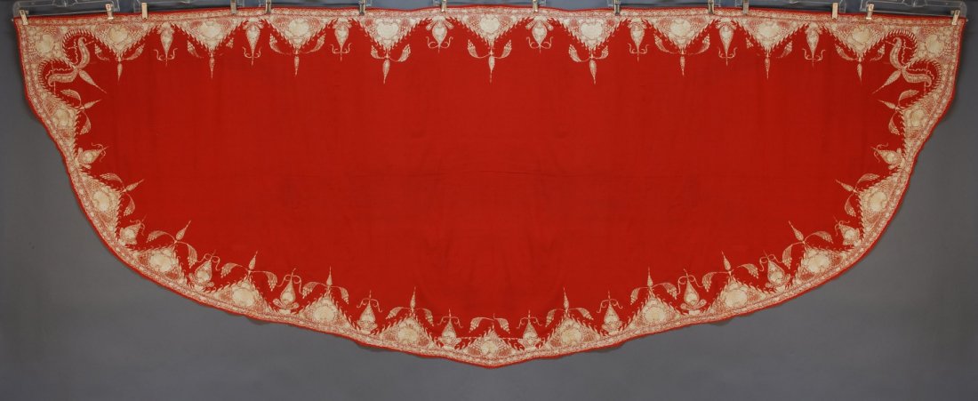 INDIAN SILK EMBROIDERED WOOL SHAWL, 19th C.: Long panel having curved underside in tomato red with a border of white silk embroidered floral. 47 x 133. SM. (Small light stains).