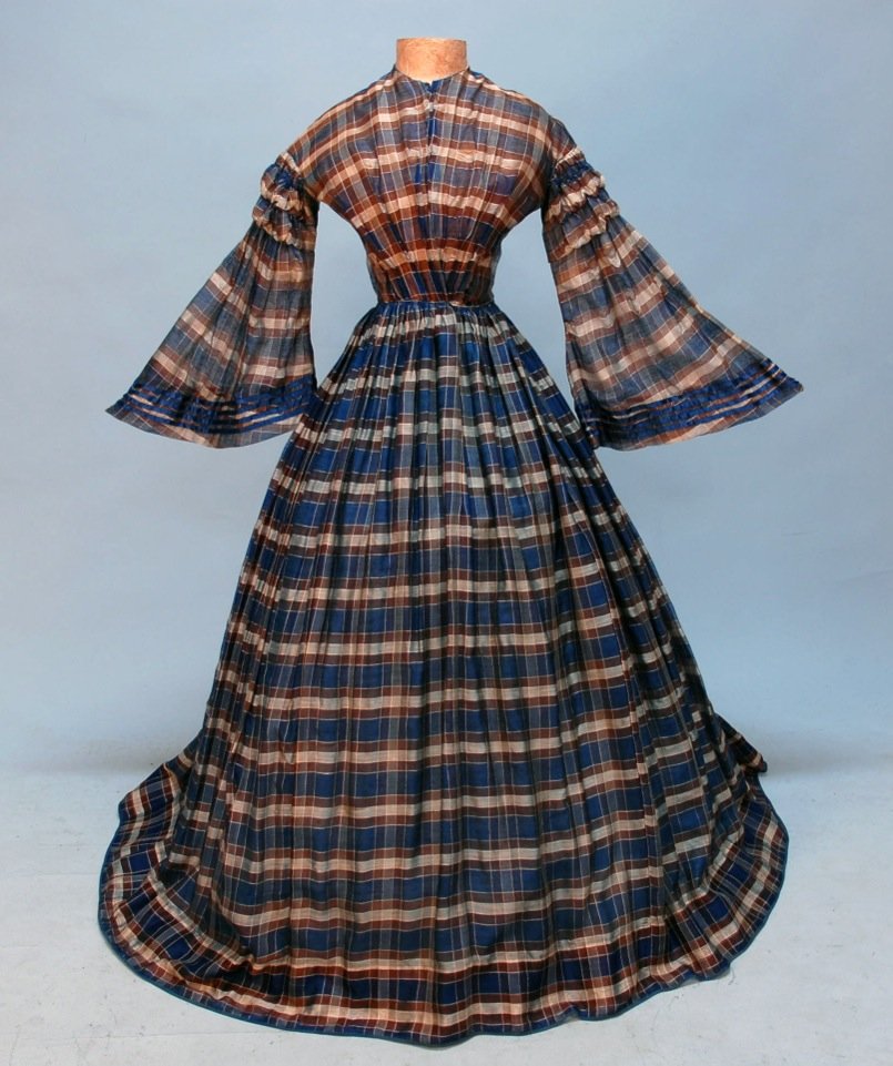 COTTON PLAID DAY DRESS and STOLE, c. 1850.: Blue, brown and white cotton gauze, having bell sleeve with ruched cap, trimmed in blue ribbon, cotton twill interior boned corset, skirt lined in blue cotton, matching stole. B-32, W-22, L-54. SM. (S