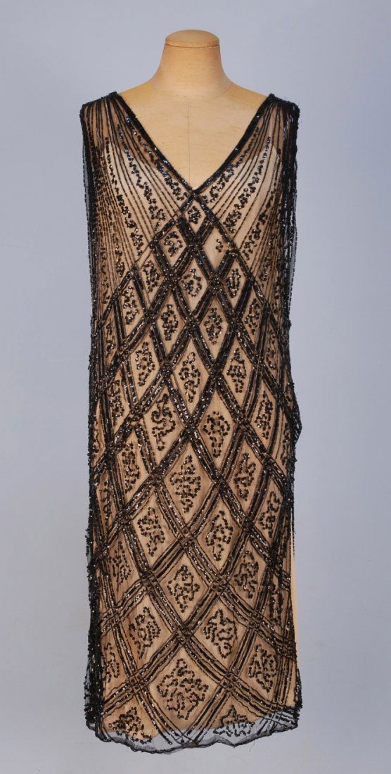 BEADED NET FLAPPER DRESS, 1920's.: Sleeveless black cotton net with black bugle beads, sequins and paillettes in a diamond lattice pattern, V-neck and back and one side slit to hip. B-42, L-43. SM. (Lacking under-dress, minor bead loss