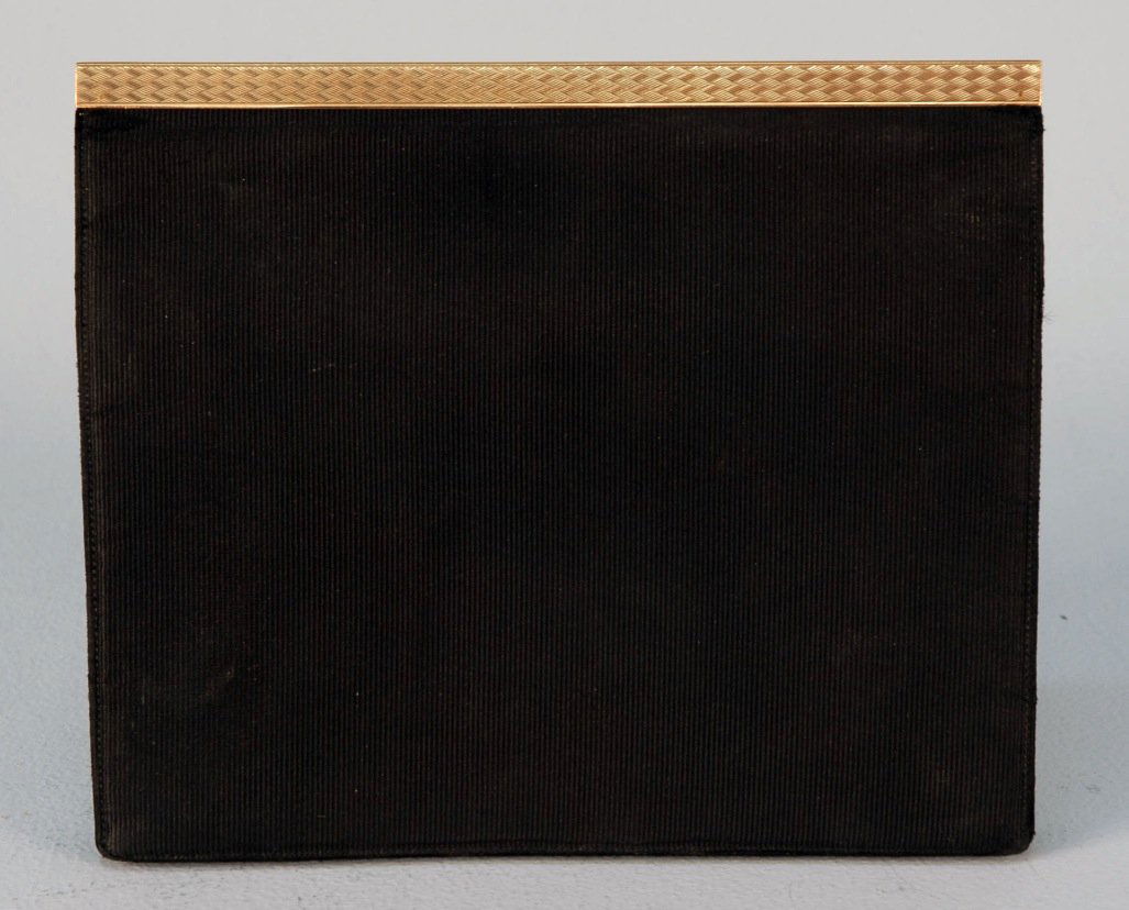 GOLD FRAMED SILK CLUTCH, MID 20th C.: Retailed by Cartier, black silk bengaline rectangle having bellows interior with four open pockets and outer snap flap pocket below full front flap framed at top with engraved 9K gold, gilt stamp "Car