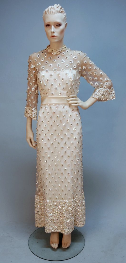 BEADED and SEQUINED EVENING DRESS, c. 1970.: White net with 3/4 sleeve over white crepe strapless under-dress, empire waist with wide crepe waistband and bow decorated with clusters of square white iridescent sequins and crystal beads having hea