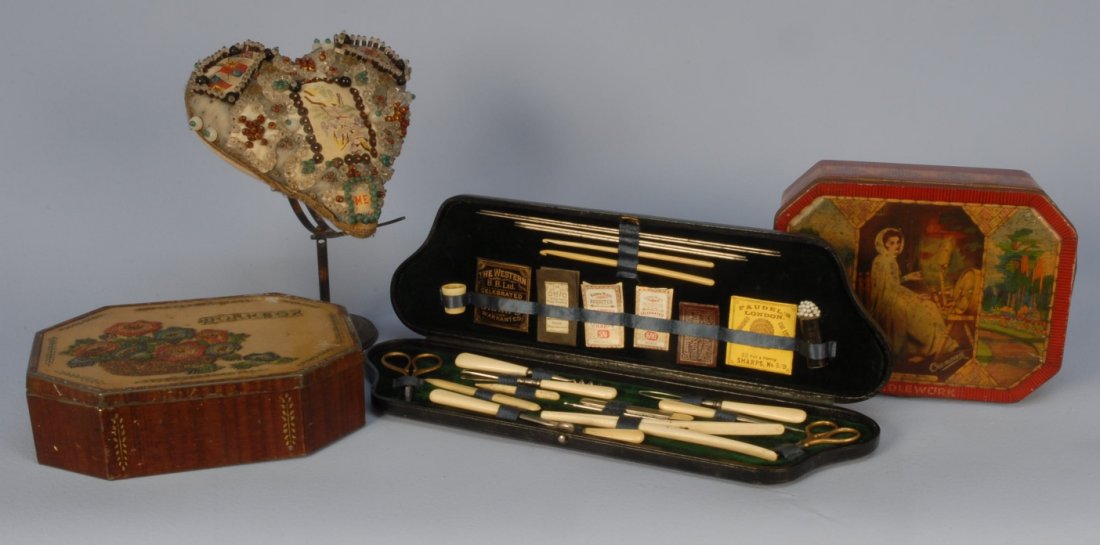 LOT of SEWING RELATED ITEMS, c. 1900.: Consisting of a heart shaped pincushion decorated with silk and paper appliques, pinned beads and sequins, 7 1/2 inches (some losses). One needlework tool case with bone handled tools, scissors, needl