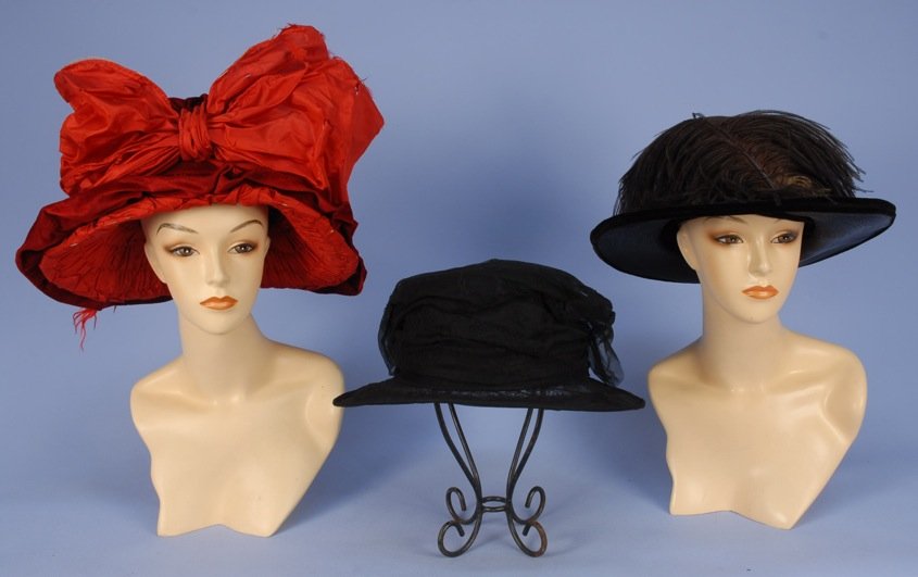 THREE HIGH CROWN HATS, 1905-1925.: One deep red velvet with huge wired taffeta bow (bow torn). Two black Henri Bendel label: One straw with ostrich plume, one lace on wire frame. Good-excellent. MMA.