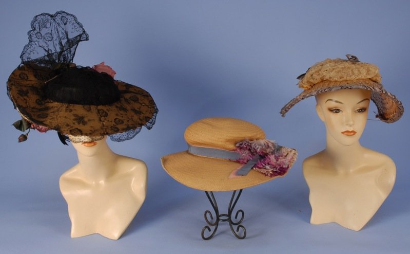THREE WIDE BRIM STRAW HATS, EARLY 20th C.: One having turned up brim with velvet bow and cloth roses to the underside, black lace crown, overbrim with wired ruffle and rose. One Paris label oval with ribbon band and silk flowers. One raffia pa