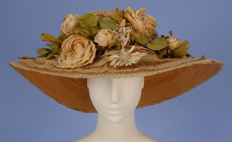 LACE and STRAW WIDE BRIM HAT, 1910.: Natural straw with concentric bands of cream lace decorated with cloth roses and daisies. 20 x 4 1/2. (Some darkening of lace, lining damaged) good. MMA.