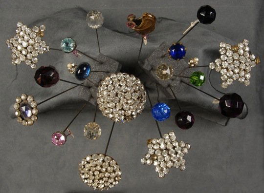 LOT of JEWELED HAT PINS, LATE 19th - EARLY 20th C.: Including faceted "jewels", rhinestones and one Art Nouveau butterfly form signed A. Vaille. 22 pieces. Length, 4 - 12 1/2 inches. Together with a glass pin holder with metal overlay (lacking stopper)
