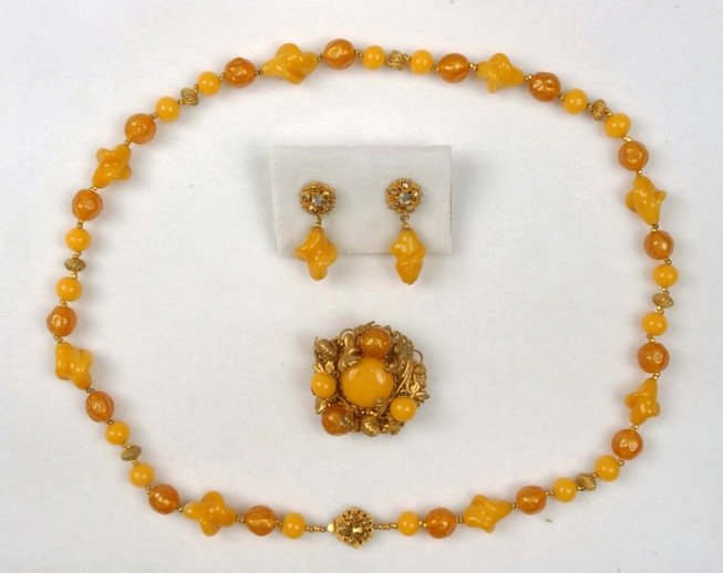 MIRIAM HASKELL DEMI PARURE.: Necklace of caramel and amber art glass beads with gilt metal bead spacers. Round pin having high relief gilt poppies around beads and center cabochon on filigree backing. Matching drop ear clips. Sig