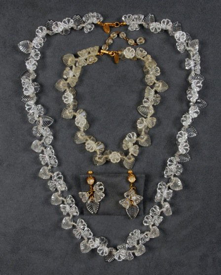 SET of MIRIAM HASKELL FLOWER JEWELRY.: Two necklaces having clear molded glass leaves and clear plastic flowers, matching ear clips. Signed. Necklaces 8 - 14 inches. Excellent.