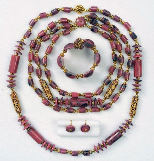 MIRIAM HASKELL FOUR PIECE DEMI PARURE.: Two marbelized purple plastic bead and filigree covered cylinder necklaces, ear clips and memory wire bracelet. Signed. Necklaces 14 inches and 10 inches. (Minor verdigris) good.