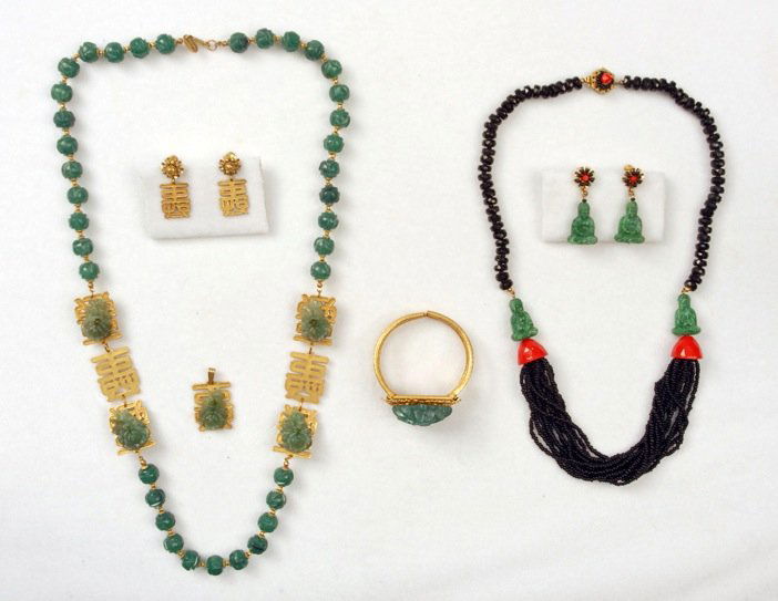 TWO MIRIAM HASKELL ASIAN INSPIRED JEWELRY SETS.: Carved plastic bead necklace with gilt separations set with green flowers upon Chinese characters, 15 inches, with matching pendant, clamp bracelet and ear clips. Black multi strand necklace with plas