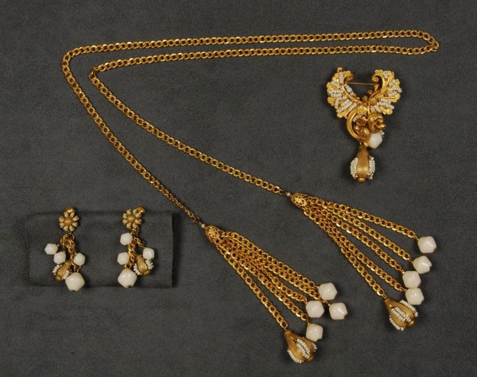 MIRIAM HASKELL DEMI PARURE.: Gilt metal lariat necklace with link chain having six-chain tassels, five having ivory glass bicone finial, one with gilt drop decorated with seed beads, asymmetrical pin with crossed gilt leaves, bea