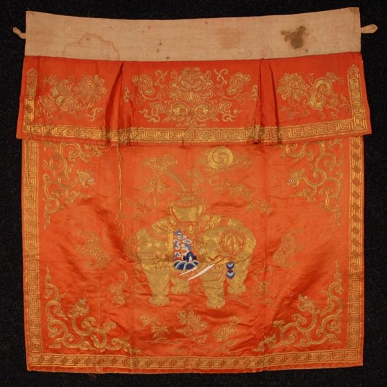 CHINESE METALLIC EMBROIDERED SKIRT PANEL, c. 1900.: Orange silk satin decorated with couched gold threads and blue and white satin stitch depicting elephant, urn and stylized floral, having apron top. 36 x 37. (Some broken threads and wear) fair.