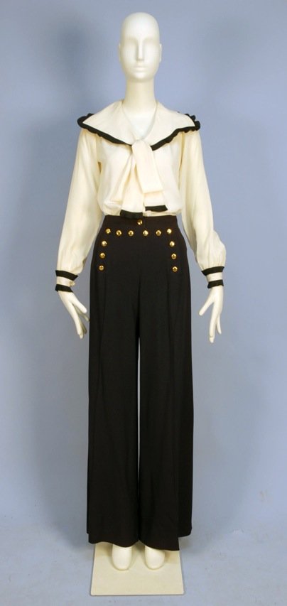 SAINT LAURENT RIVE GAUCHE SILK BLOUSE and SAILOR PANTS,: Cream silk blouse having wide collar with tie and cuff trimmed in pleated navy silk, navy wide leg high waisted fall front trousers with brass buttons. Labeled. B-35, W-25, L-44 1/2. (Two small spots 