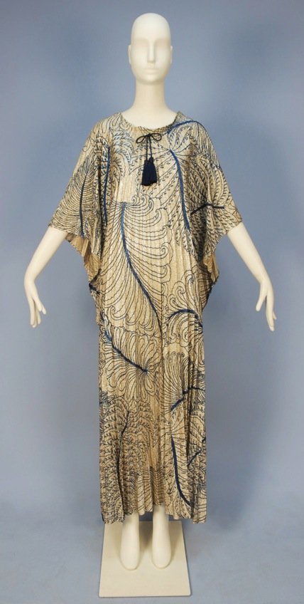 YVES SAINT LAURENT PRINTED LUREX CAFTAN, 1970's.: Square cut metallic silver printed with large scale tropical foliage in blue, having accordion pleats and drawstring neckline. Labeled "Yves Saint Laurent". L-57. Excellent.