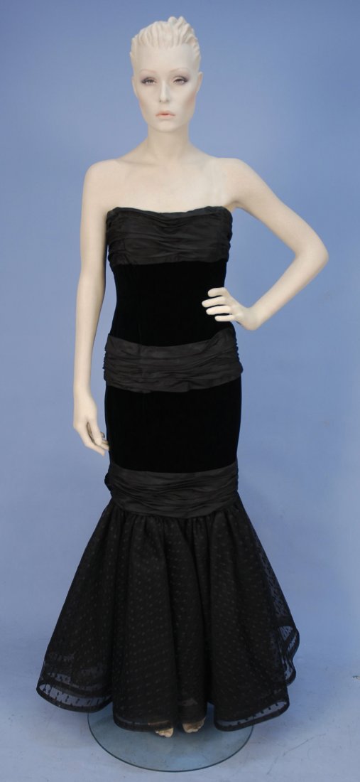BILL BLASS SILK and VELVET STRAPLESS GOWN, 1970's.: Black having ruched taffeta band at boned bust, waist and above the knee, each having oversized bow at back, dotted net flared skirt, back zipper and silk lining. Labeled. B-30, W-25, H-34, L-49. Exce