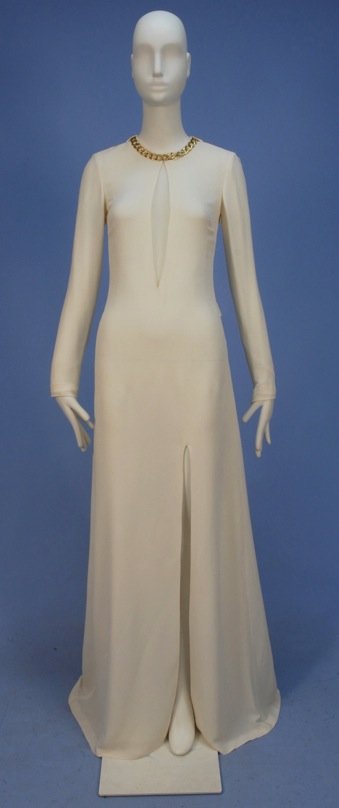 ALEXANDER McQUEEN WHITE SILK CREPE EVENING GOWN, 21st C: Long zippered sleeve, tiny collar with gilt link chain above cutout to waist having mesh insert, flared skirt with off center slit to top of thigh, half self belt, silk lining, side and back zipper. L