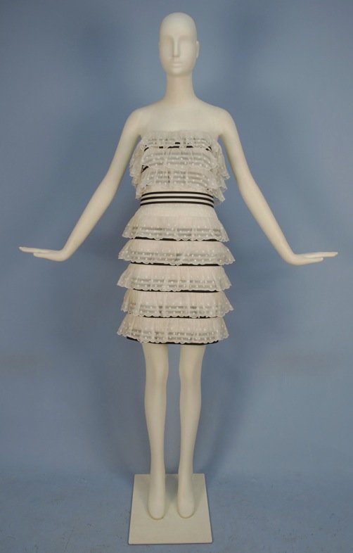 CHANEL BOUTIQUE STRAPLESS MINI DRESS, 20th C.: Fitted white cotton having boned bodice, comprised of black and white grosgrain ribbon bands beneath scalloped ruffles of dotted Swiss, ribbon covered belt. Labeled. B-34, W-26, H-34, L-31. Excellent.