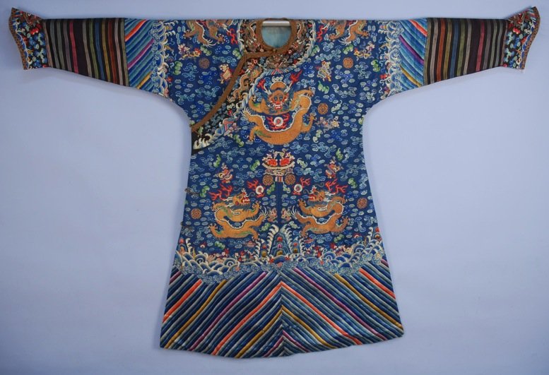 CHINESE SILK EMBROIDERED NINE DRAGON ROBE, EARLY 20th: Cobalt satin having couched metallic gold dragons and vibrant satin stitched clouds, bats, flaming pearls, Buddhist emblems, etc., li shui border, striped lower sleeve, horse hoof cuff and metallic br