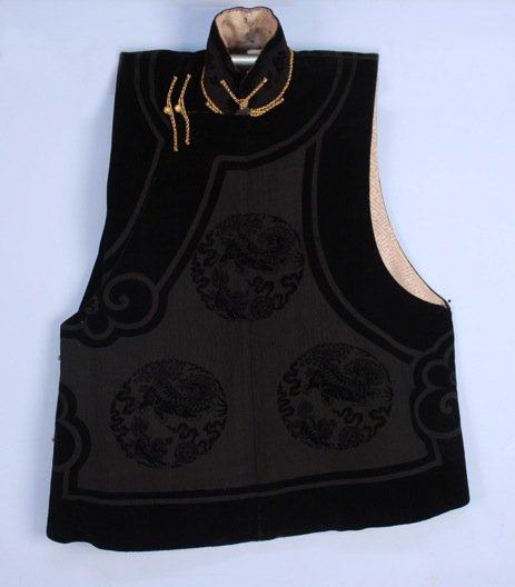 CHINESE VOIDED VELVET WAISTCOAT, 1927.: Black silk having roundels with shi-shi and banded trim with scrolls, stand collar, loop closures. 33 x 34. (1/2 inch hole on back, brocade lining tearing in neck area) good. FIT.