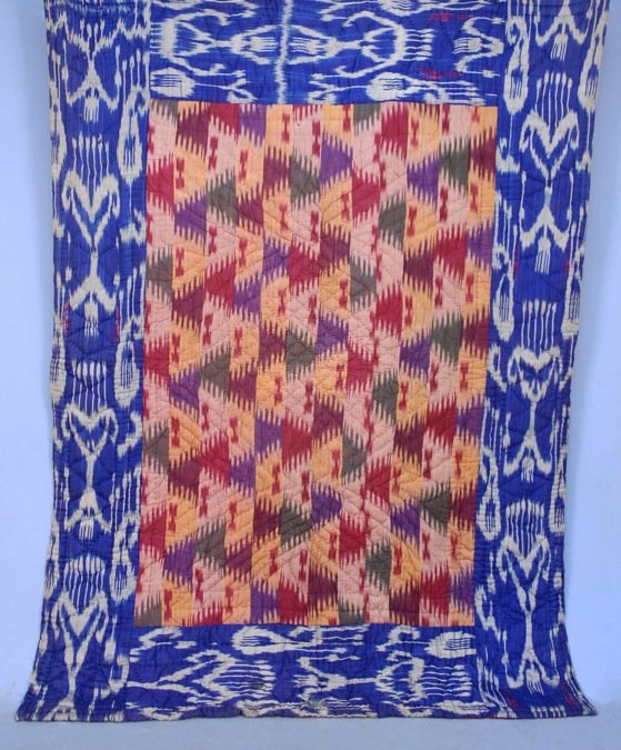 IKAT QUILTED BED COVER, 20th C.: Red, yellow, green and purple silk ikat fabric with blue and white ikat border, heavy cotton batting and backing. 88 x 66. Excellent.