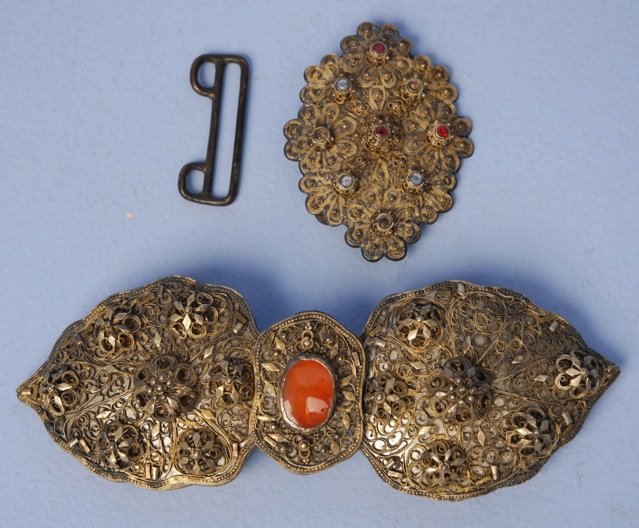 TWO BULGARIAN BELT BUCKLES, 19th C.: Both gold metal filigree over silver metal: One having center set with oval carnelian, 7 x 2 1/2 (missing one raised flower head). One oval set with glass stones, 2 1/4 x 3 (three stones missing). Goo