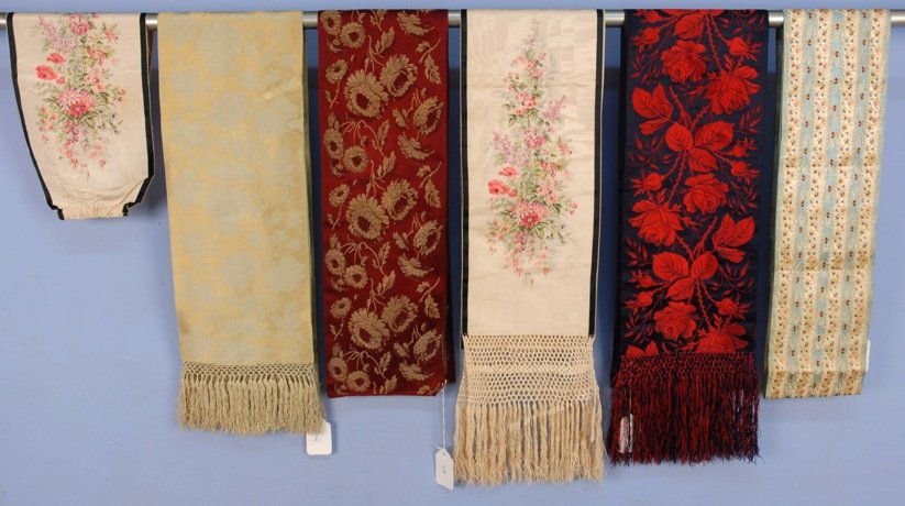 FOUR FLORAL BROCADE SILK SASHES, LATE 19th C.: Including two French with rose pattern and knotted fringe. Together with a warp printed moire silk sash with matching cummerbund. 6 3/4 - 9 inches wide, 82 - 108 inches long. Good-excellent. MMA.