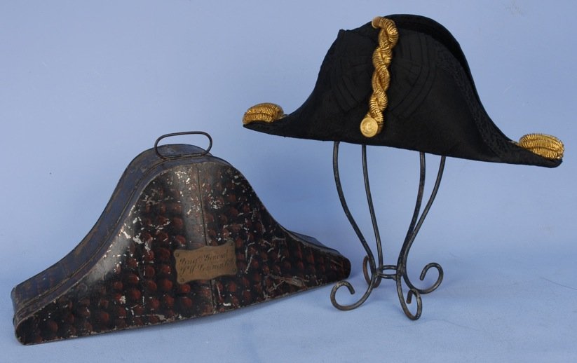 GENTS ENGLISH BICORNE HAT and CASE, 1st HALF 19th C.: Black beaver trimmed with passementerie, faille ribbon, gold braid and coiled rope, silk lining. Labeled "Owen Harries & Co. 15, Russell Street Landport. ". Metal case with paint decoration and plaque