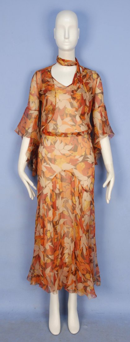 PRINTED CHIFFON GOWN and JACKET, 1930's.: Floral printed silk in autumn tones having V-neck, U-back, self belt and full lower skirt flaring from a curved seam with four hem slits, matching jacket with single neck tie and bell sleeve. B-34, W-