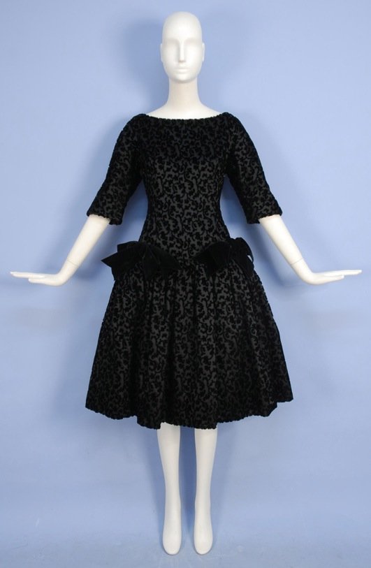 CHRISTIAN DIOR COUPE de VELOURS PARTY DRESS, 1950's.: Black short sleeve boatneck with scrolling floral design having dropped waist with two velvet bows and full skirt with crinoline. New York label. B-36, W-28, H-38, L-42. Excellent.