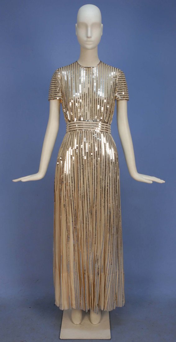 NORMAN NORELL SEQUINED CHIFFON EVENING GOWN, c. 1970.: Short sleeve cream silk with wide waistband decorated with vertical bands of silver sequins, full skirt having pleats decorated with sequin band at outer edge, separate silk underskirt. . Labeled. B-3