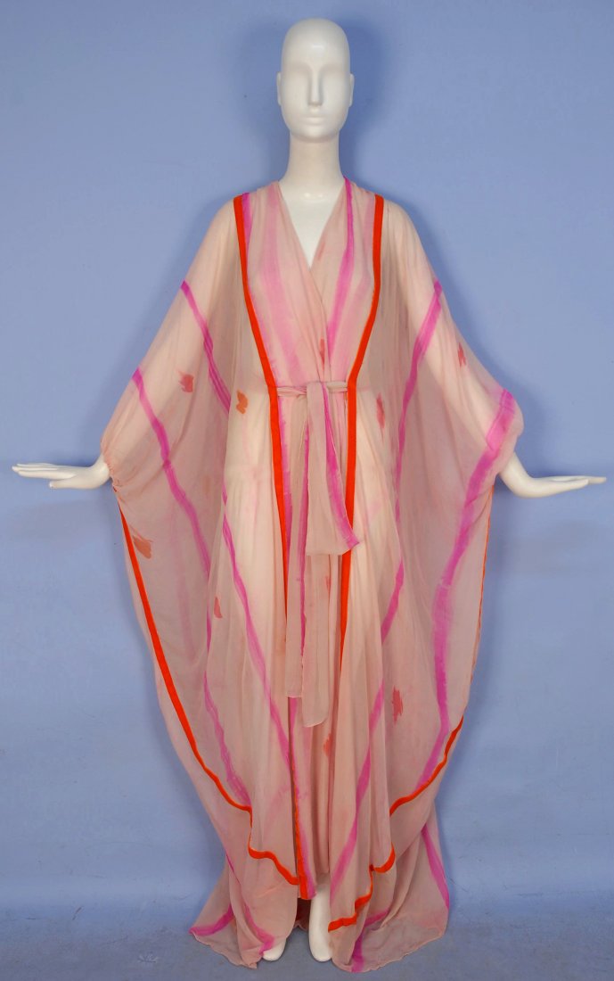 THEA PORTER PRINTED CHIFFON CAFTAN, c. 1970.: Pale pink silk printed with fuchsia dashes and stripes with applied orange velvet bands, gathered arm opening and front slits for self sash. Unlabeled. 58 x 62. (Few small tears near hem) good.