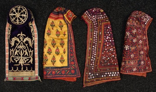 FOUR EMBROIDERED CAPS, 19th - EARLY 20th C.: Two Indian cotton having tambour work inset with mica disks. Two central Asian: One cotton with tambour floral and birds, one purple velvet with metallic embroidery. (Some losses) fair-excellent. MMA.