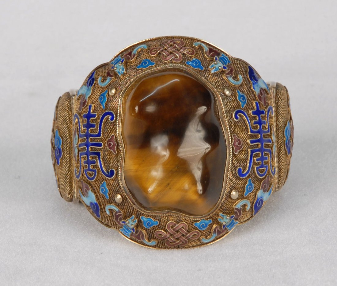 CHINESE CLOISONNE and TIGERS EYE BRACELET, 20th C.: Larger hinged cuff bracelet of finely woven gold tone mesh with colorful appliques of Buddhist symbols in cloisonne, large natural shaped tiger's eye stone set in center. Marked "Silver". Stone 1 1/2 