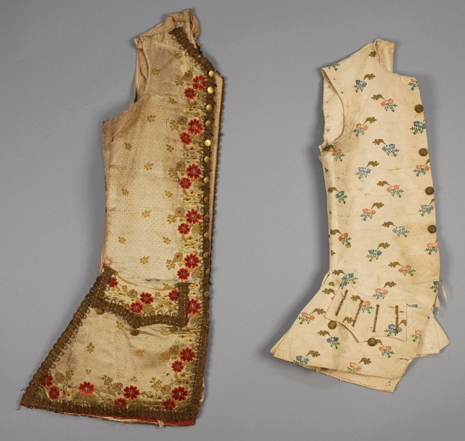 TWO GENTS EUROPEAN SILK WAISTCOATS, MID 18th C.: One off white satin brocade with chenille and metallic floral decoration having shaped pocket flap over V-shaped pocket, trimmed in gold galloon, gold metallic bound button holes, cotton lining, skirt