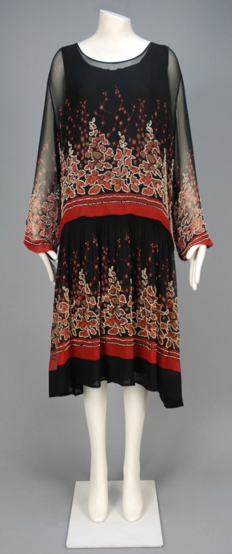 PRINTED and BEADED CHIFFON DAY DRESS, 1920s.: Black chiffon with abstract floral and graduated bands in red, rust and taupe decorated with white beads having long sleeve gathered into narrow cuff, dropped waist and gathered skirt, crepe underdres