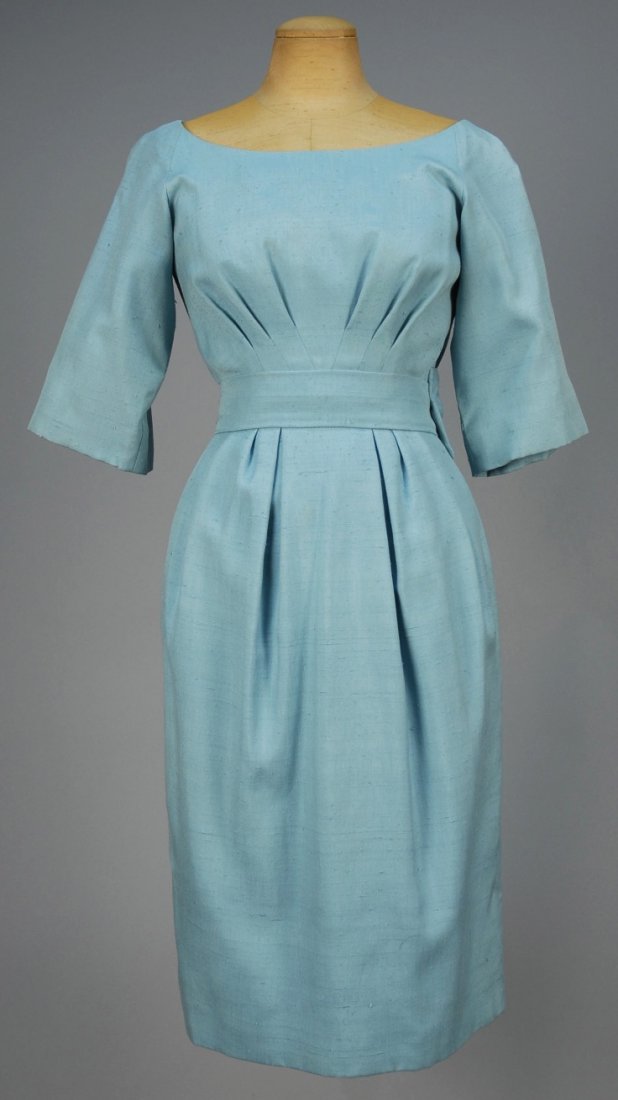 CHRISTIAN DIOR SILK DAY DRESS, 1950s.: Robin's egg blue slubbed silk boatneck with short sleeve, V-shaped bodice pleats, V-back with faux wrap and self bow and sash above narrow pleated skirt, lined in silk gazar. New York label. B-34, W-2