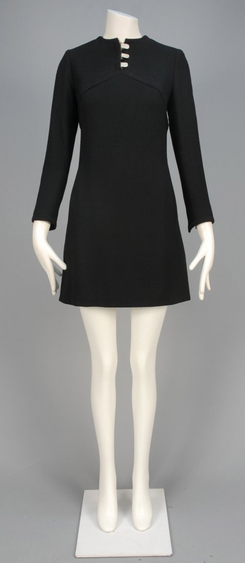 GEOFFREY BEENE CREPE COCKTAIL DRESS with RHINESTONES,: Long sleeve black wool with angled high waist having slit neckline and cuff decorated with rhinestone buckles, vertical front pockets and angled back waistline. Labeled. B-36, W-34, H-38, L-35. (One r