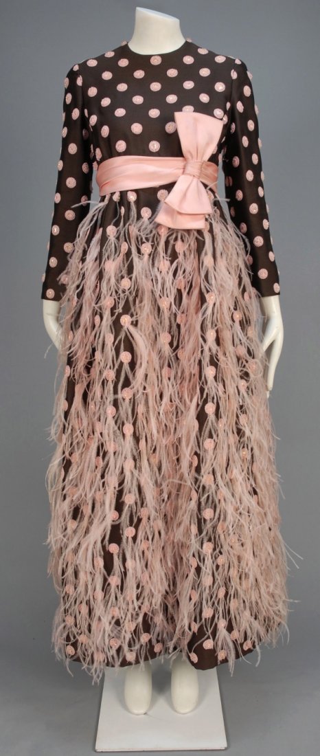 IRENE SARGENT EVENING DRESS, c. 1972.: Long sleeve brown wool twill having pink beaded polka dots with rhinestone center, the skirt appliqued with pink feathers, pink satin sash. Labeled. B-36, W-26, L-57. (Some feather and bead loss near 
