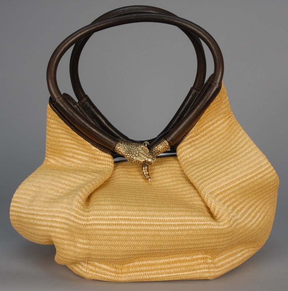 JIMMY CHOO SNAKE HANDLED RAFFIA HANDBAG.: Natural color fiber with brown leather trim and padded twin handles, one having metal snake head biting tail, one inside pocket, buckle closure. Stamped label and marked hardware. 17 x 18. Excellent.