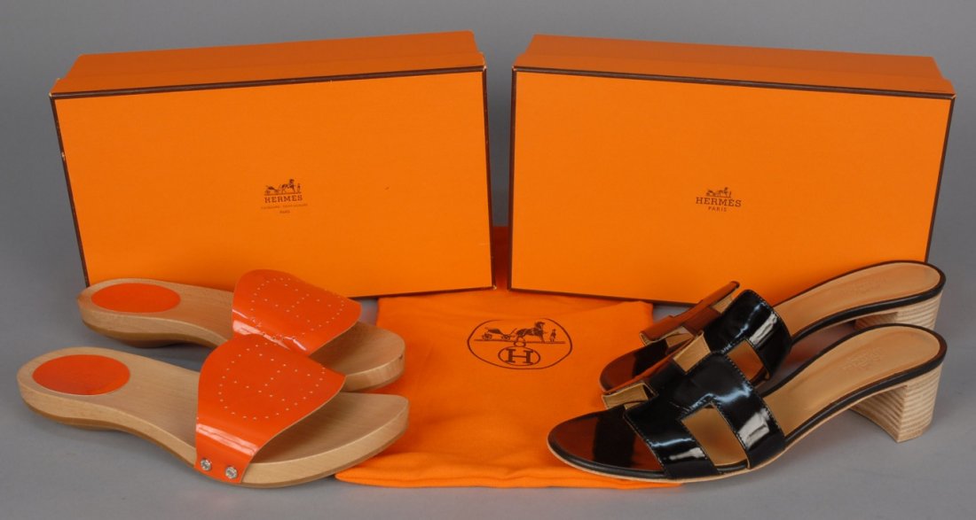 TWO PAIR HERMES PATENT LEATHER SANDALS.: One pair black with short stacked heel and logo vamp. One pair orange wooden mules with perforated logo vamp. Both with original dust bags and box. Marked size 38. Excellent.