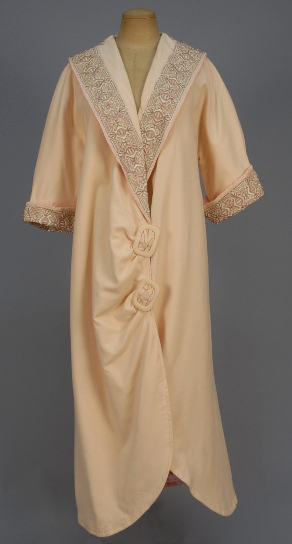 SILK EMBROIDERED WOOL TEA COAT, c. 1905.: Cream felt having shawl collar with appliqued net embroidered with pink and white silk and metallic threads, matching cuff, the front and back ruched into faux self buckles, hook & eye closures and sa