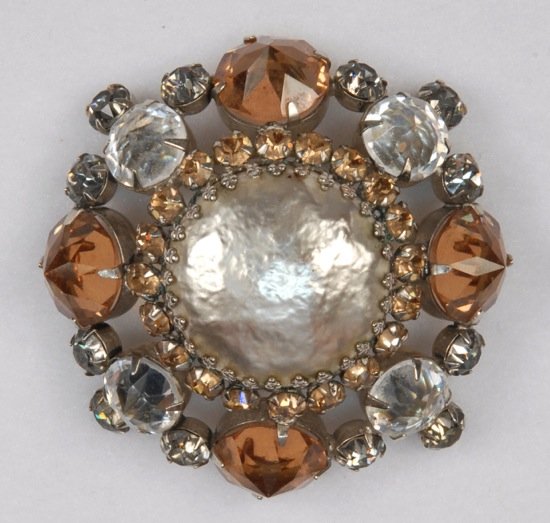 LARGE SCHREINER BROOCH, 20th C.: Circular pin with faux pearl surrounded by topaz colored and clear glass prong set "jewels". Marked with stamped oval tag. 2 1/2 diameter. Excellent.