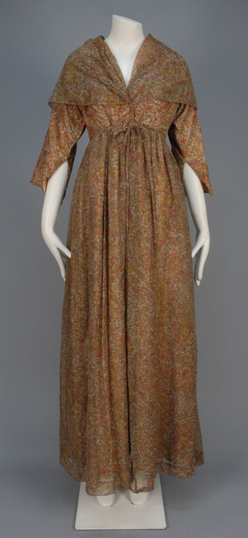BONNIE CASHIN PRINTED SILK LONG DRESS, MID 20th C.: Polychrome paisley print with sheer outer layer having shawl collar, wide 3/4 sleeve, full skirt and self belt and front buttons. Labeled. B-36, W-26, L-58. (Belt torn) very good.