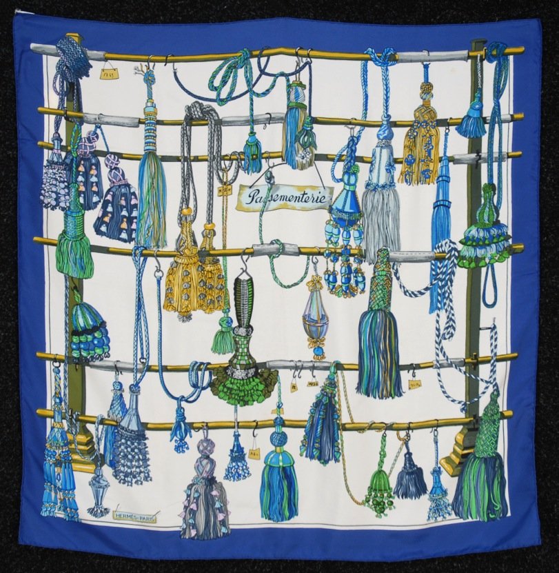 HERMES PRINTED SILK PASSEMENTERIE SCARF, ISSUE DATE: White twill ground decorated with elaborate corded tassels, script "Passementerie" and blue border, artist Francoise Heron. Labeled within design. 34 x 34 1/2. (Small stain) very good.