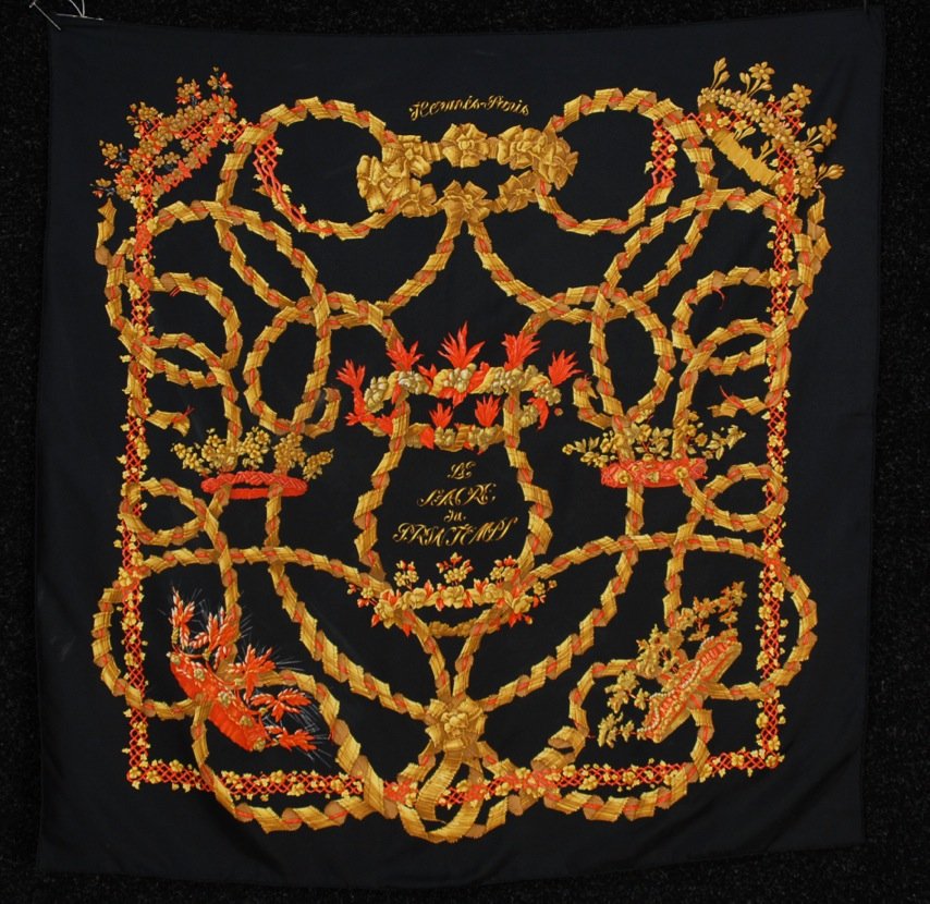 HERMES PARIS "LA SACRE du PRINTEMPS" PRINTED SILK: Orange and gold ribbon and floral pattern on black twill ground by artist Henri d'Origny. Labeled within design. 34 x 35. Excellent.