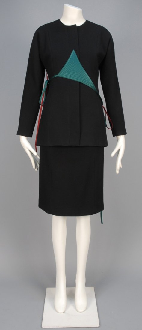 GEOFFREY BEENE WOOL SKIRT SUIT with SATIN APPLIQUE,: Black crepe with jewel neck and hidden buttons appliqued with topstitched asymmetrical satin triangles having long side ties, matching narrow skirt. Labeled. B-36, jacket L-27, W-26, H-37, skirt L-23.
