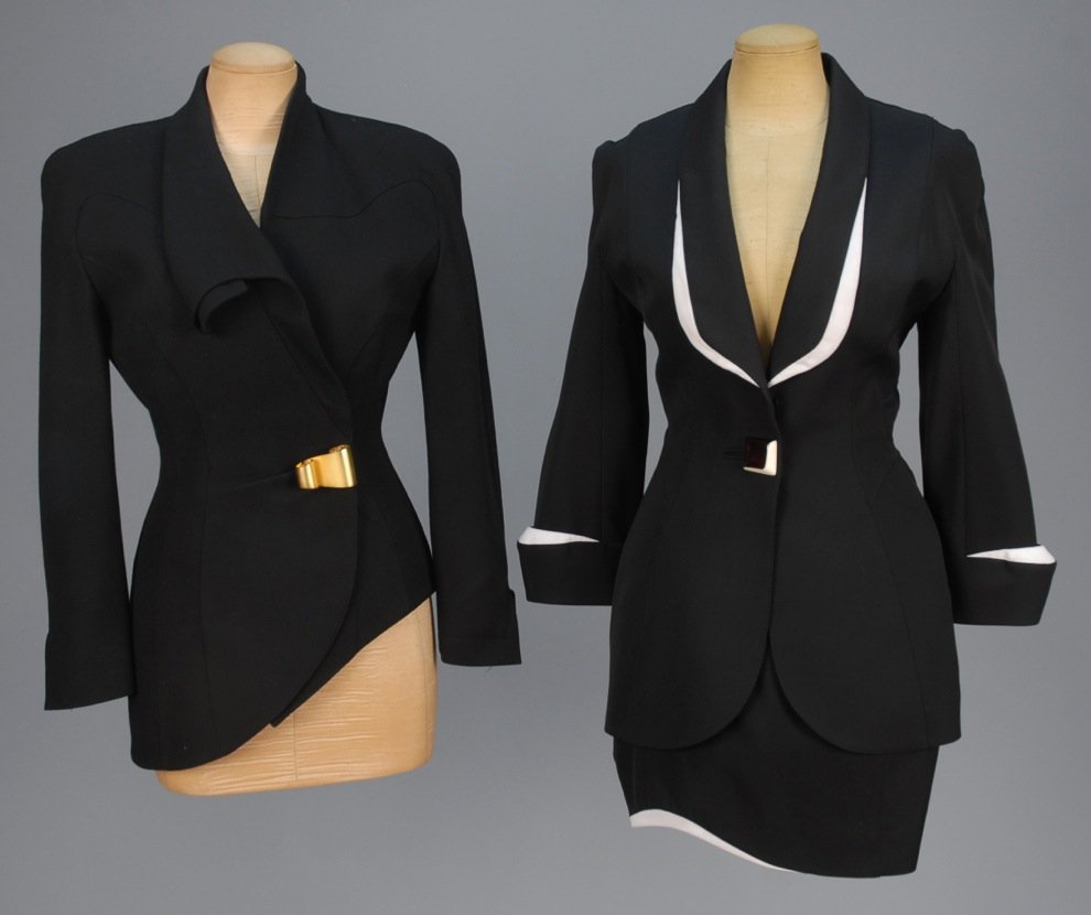THIERRY MUGLER SKIRT SUIT and JACKET, 1980s.: Black V-neck suit having chamfered and curved lapel and cuff with white trim, single 2-tone button and matching skirt with curving hem. B-32, jacket L-29, W-23, H-36, skirt L-18. Asymmetrical black ja