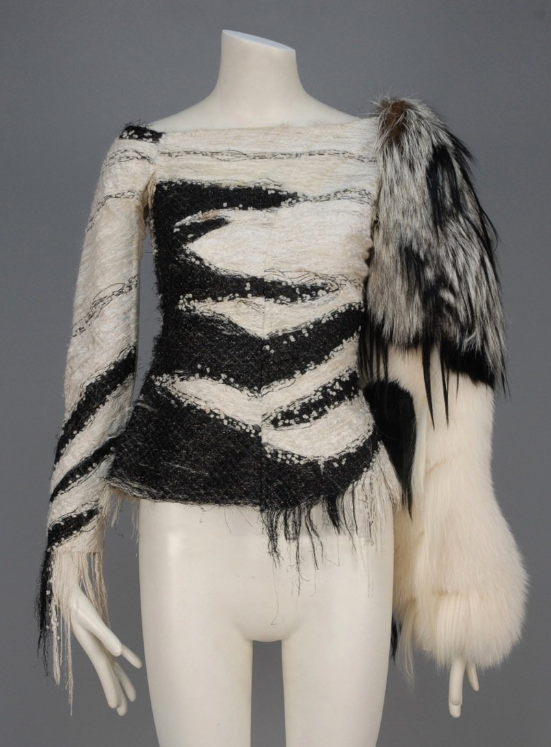 UNLABELED DESIGNER SAMPLE NOVELTY TOP with FUR SLEEVE.: Black and white long sleeve boat neck woven with looped threads, mylar and diamond grid having stretch mesh undersleeve and side gore, one sleeve made of mixed furs with slit along the outer seam. B-3