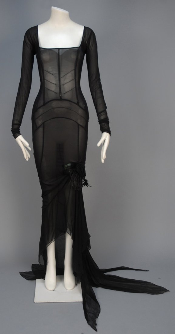 DOLCE & GABBANA TRAINED EVENING GOWN.: Long sleeve black stretch chiffon with square neck bodice having long exterior stays, pieced bias-cut skirt having irregular hem and gathered train, front slit with self flower and feather decoration.