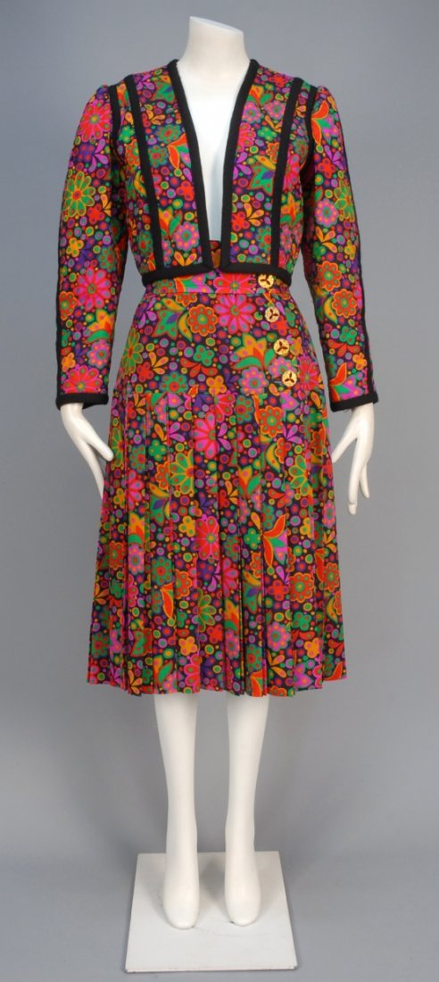 YVES SAINT LAURENT RIVE GAUCHE FLORAL PRINTED WOOL: Stylized floral in brilliant hues, collarless cropped and quilted jacket trimmed with black wool braid, matching wrap skirt with wide waistband, gilt filigree buttons set with red jewels, pleated belo